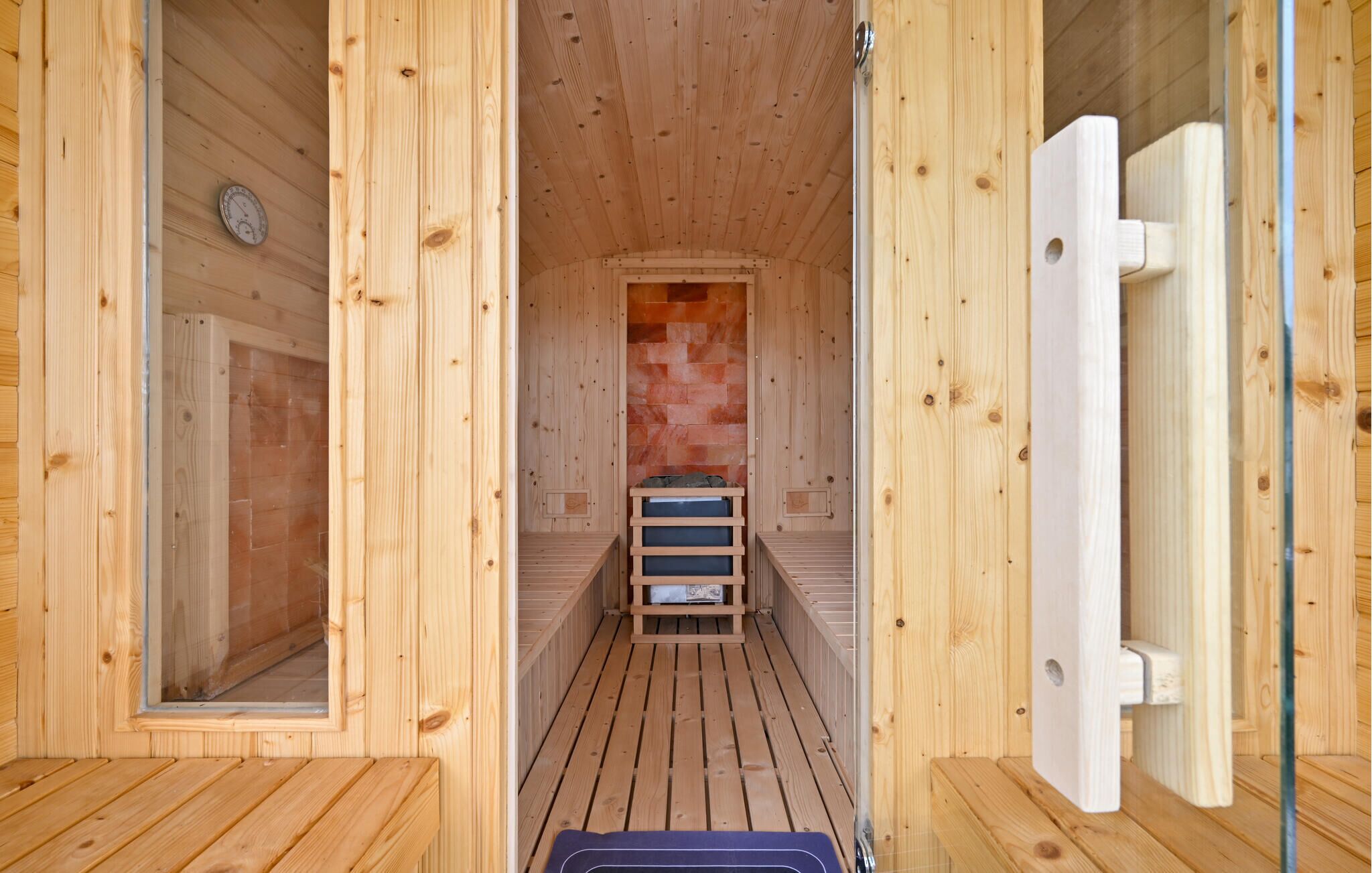 Un sauna en bois avec un sol carrelé, un banc et une horloge murale.