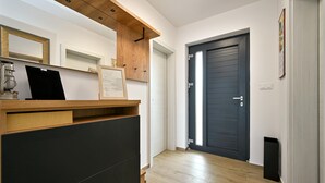 Un pasillo con un mostrador de recepción de madera, un certificado enmarcado y una puerta oscura.