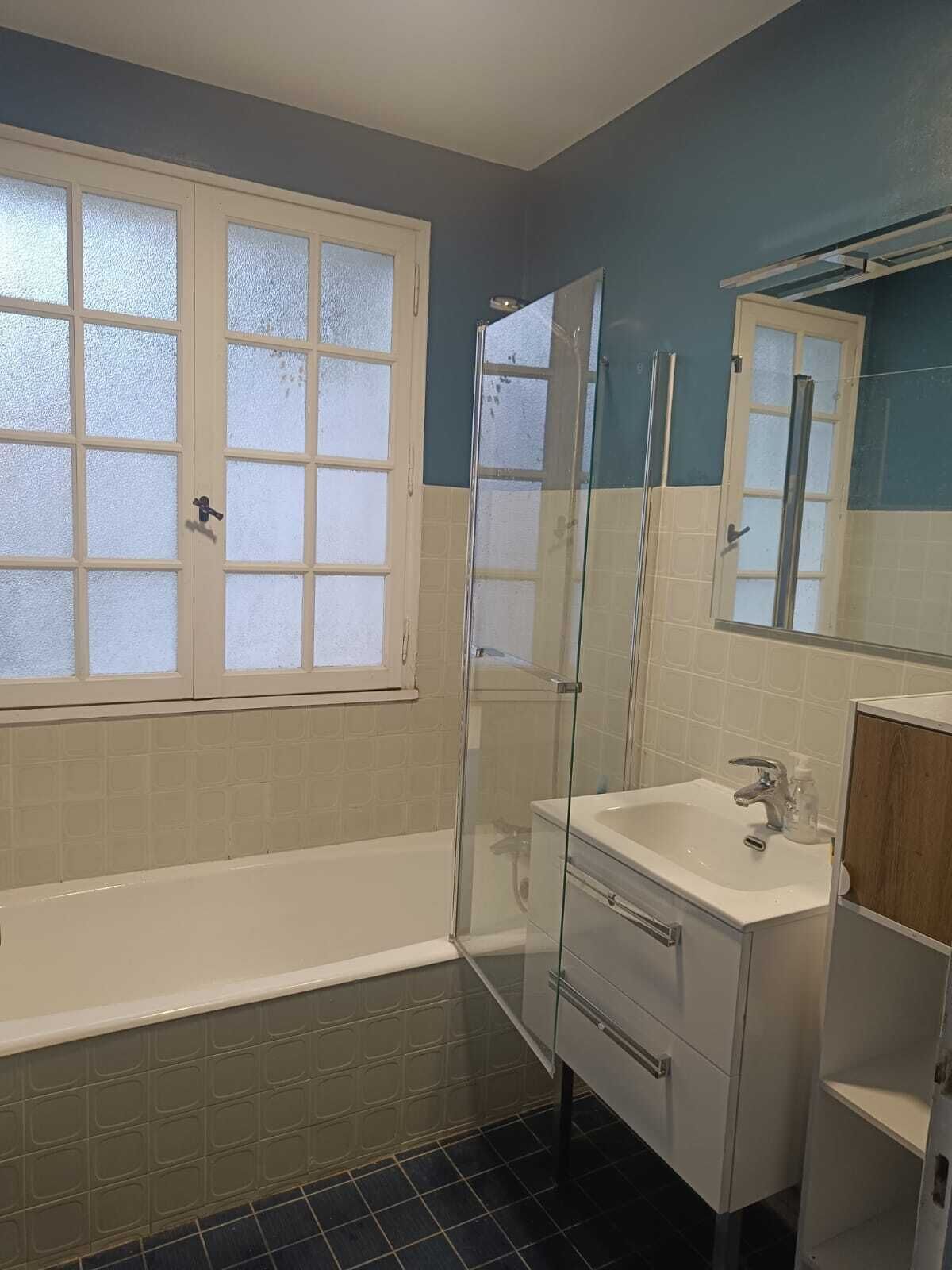 A bathroom with a bathtub, a glass shower enclosure, a sink, and a mirror.