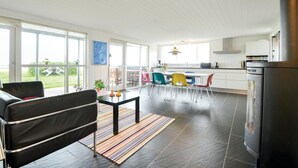 A modern kitchen with a large island, white cabinetry, and a stainless steel refrigerator. - Cozy home in Hemmet with WiFi (Hemmet)