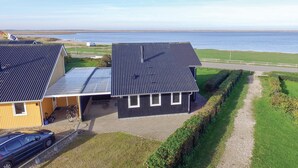 A modern two-story house with a metal roof, a garage, and a driveway leading to a paved path. - Cozy home in Hemmet with WiFi (Hemmet)