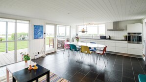 A modern kitchen with a dining area, large windows, and a view of the outdoors. - Cozy home in Hemmet with WiFi (Hemmet)