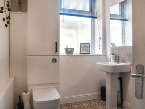 Un baño con inodoro, lavamanos y ventana con persianas.