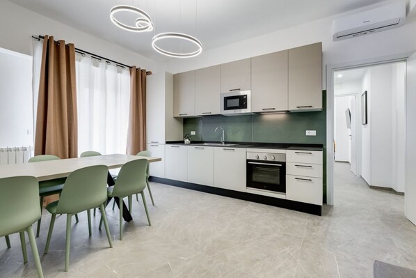 A modern kitchen with a dining area, including a table and chairs, and a built-in oven. - BDC - Mariposa new 3BDR in S.Giovanni (Roma)