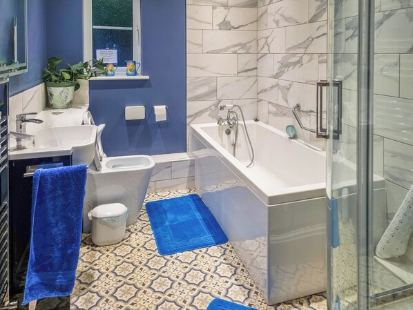 A modern bathroom with a bathtub, a toilet, a sink, and a glass shower enclosure.