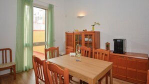 A dining area with a wooden table and chairs, a cabinet with glass doors, a water dispenser, and a view through a window with green curtains. - Awesome home in Siracusa with WiFi (Siracusa)