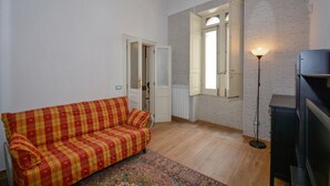 A small living room with a sofa, a radiator, a window with open shutters, and a standing lamp. - Awesome home in Siracusa with WiFi (Siracusa)