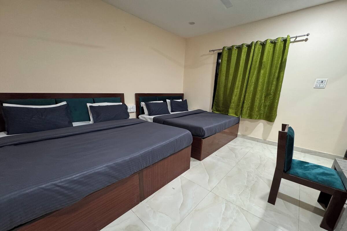 Una habitación de hotel con dos camas individuales, un cabecero de madera, una cortina verde y una silla de madera.