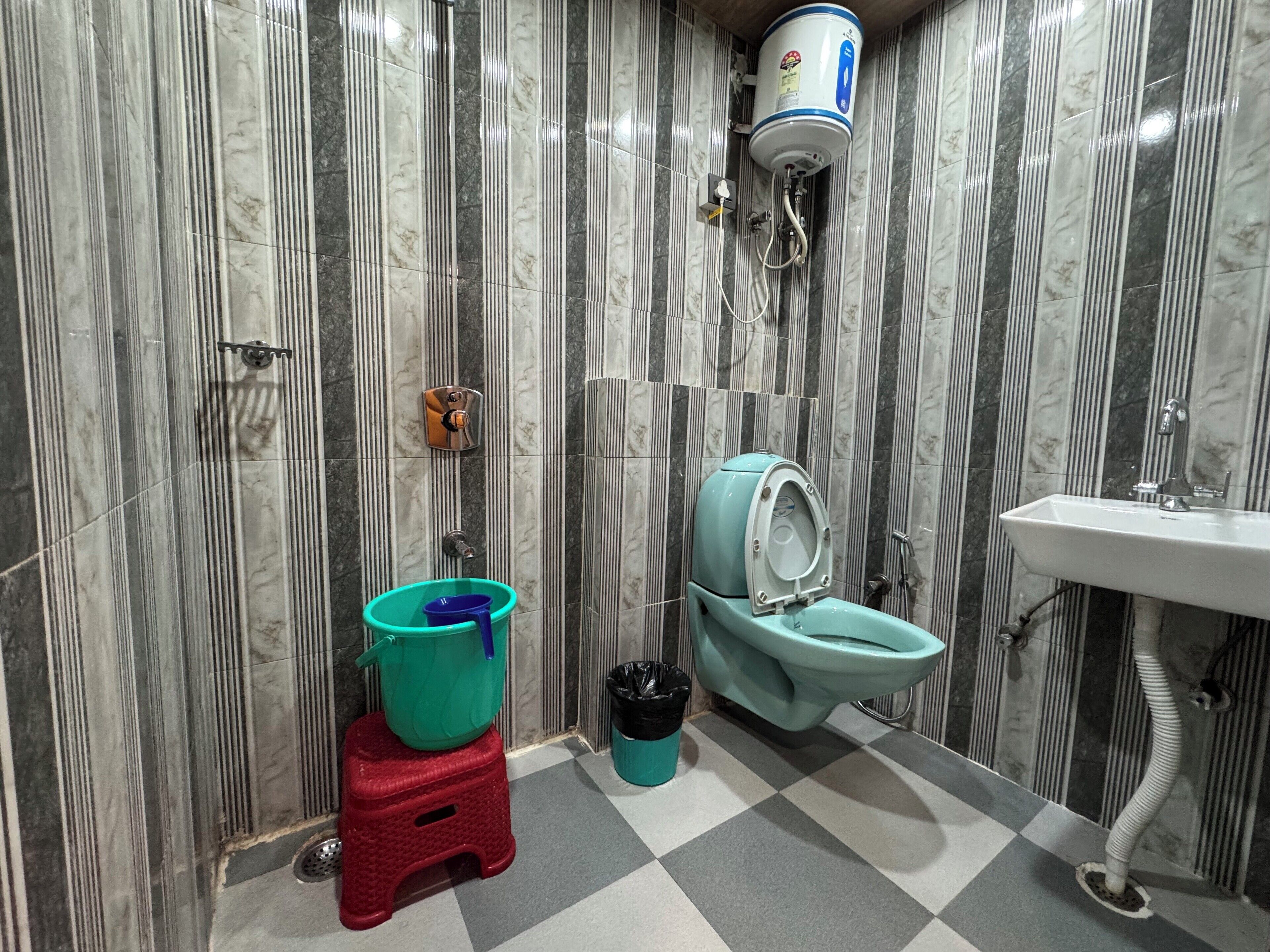 Ein Badezimmer mit Toilette, Waschbecken und Warmwasserspeicher.