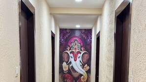 Un pasillo con un mural de una deidad, puertas a ambos lados y suelo de baldosas.