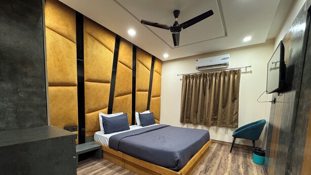 Un dormitorio moderno con una cama de madera, un ventilador de techo, un equipo de aire acondicionado y una silla azul.