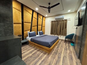 Une chambre à coucher moderne avec un lit en bois, un ventilateur de plafond, un appareil de climatisation et une chaise bleue.