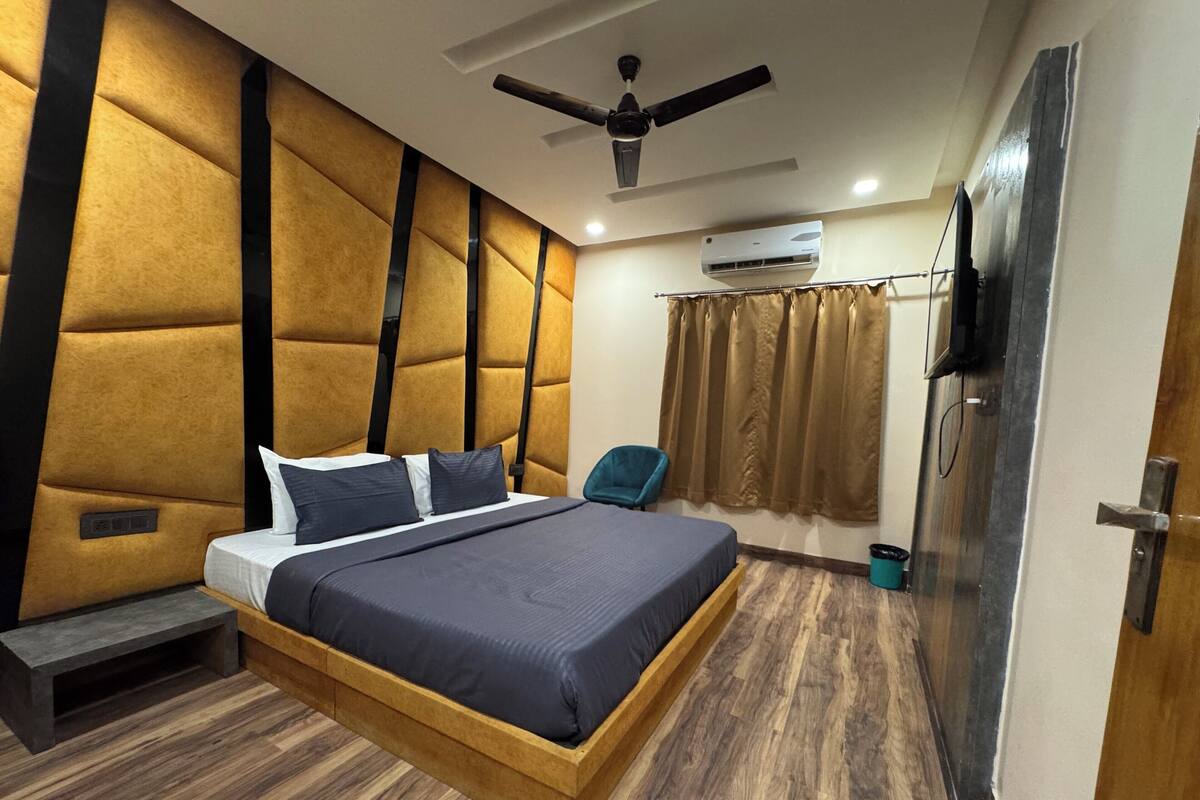 Un dormitorio moderno con una cama de madera, un ventilador de techo, un equipo de aire acondicionado y una puerta con manija.