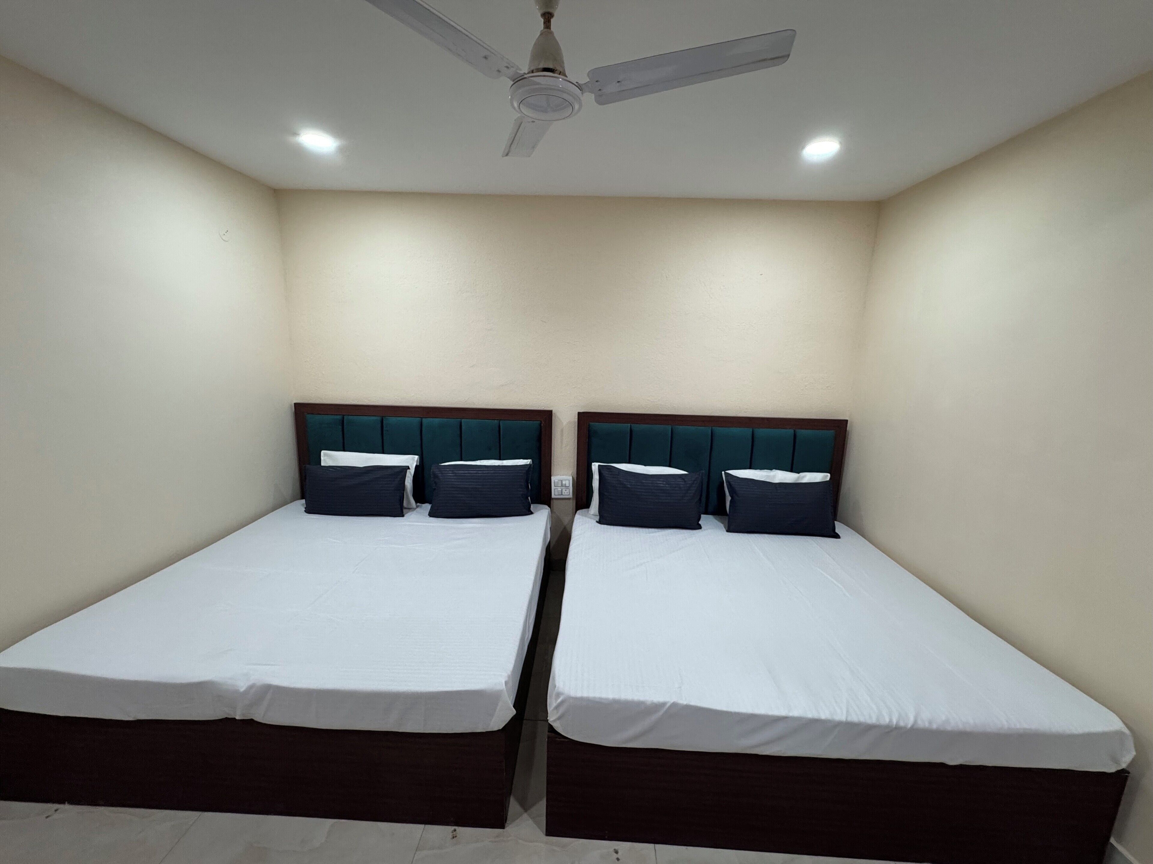 Une chambre avec deux lits, chacun doté d’une tête de lit en bois et de draps blancs.