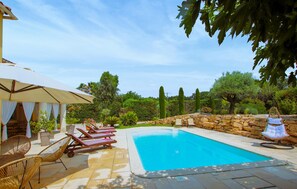 A swimming pool with lounge chairs and an umbrella, surrounded by stone walls and greenery. - Lovely home in Sarrians with private swimming pool, can be inside or outside (Sarrians)