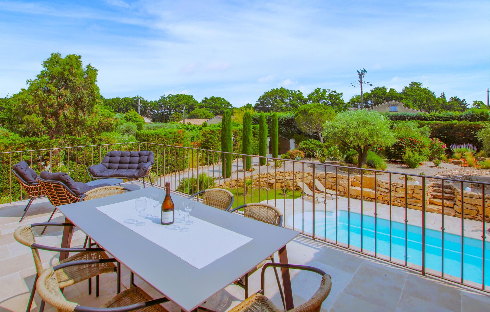 Une terrasse avec une table et des chaises, une piscine et une vue sur le jardin environnant.