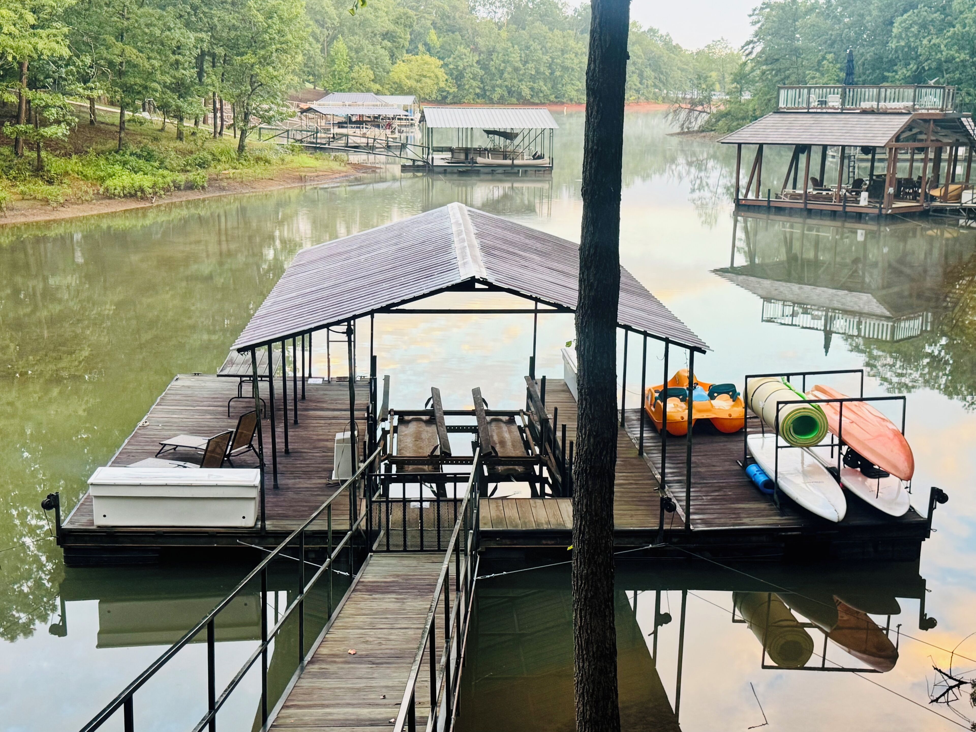 A floating dock with a covered seating area, a boat, and a kayak.