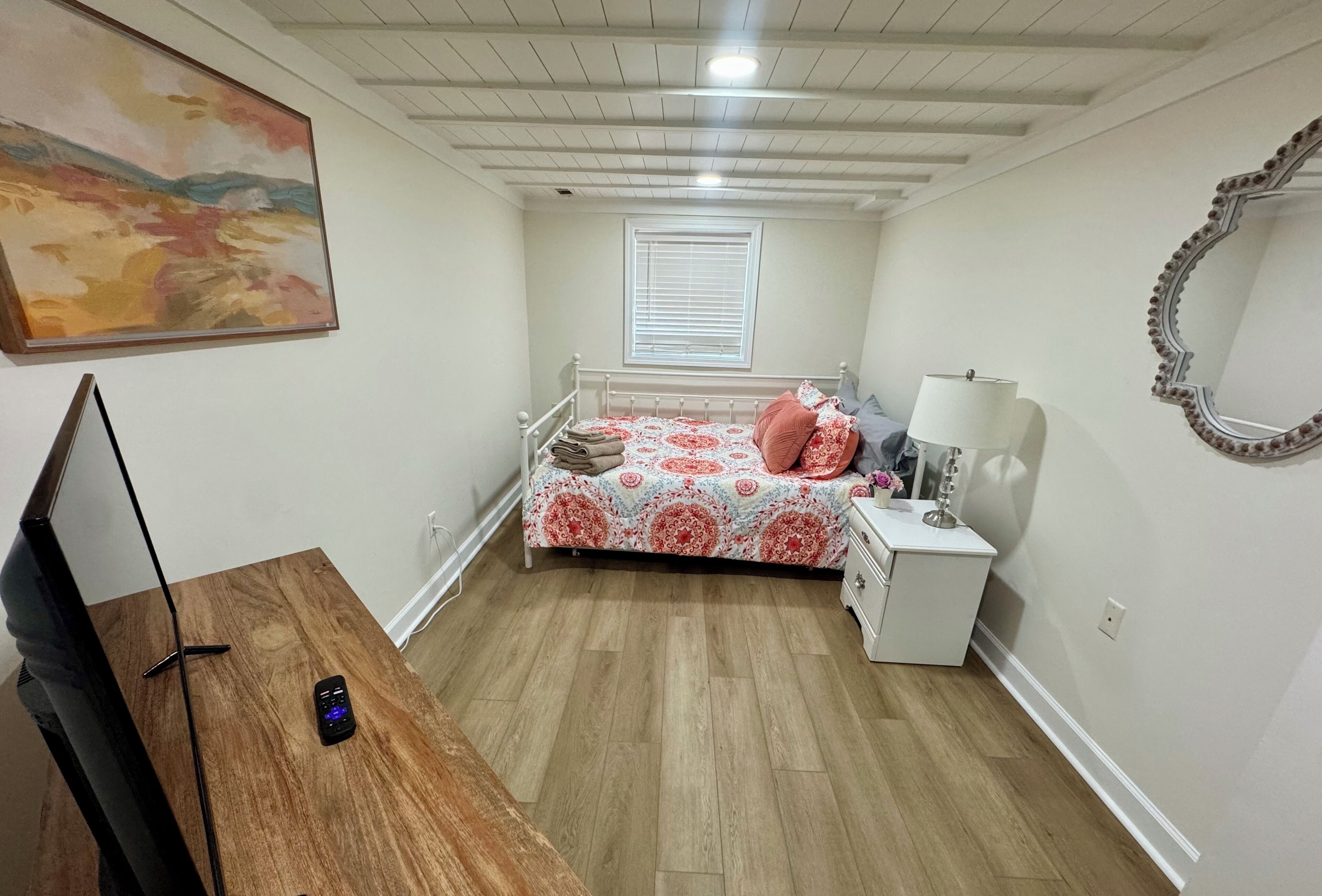 Ein Schlafzimmer mit Bett, Nachttisch, Lampe und einem Bild an der Wand.