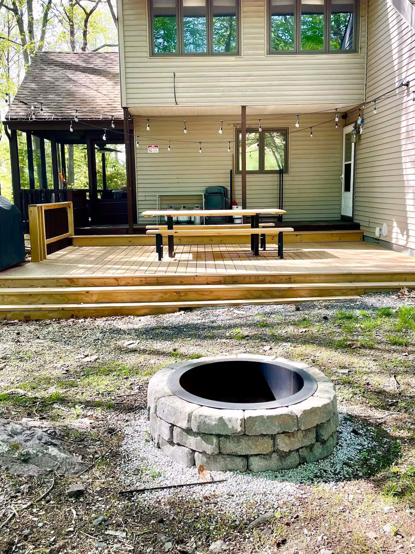 A covered patio area with a picnic table and benches, a stone fire pit, and a gazebo.