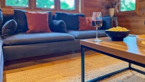 Un salon chaleureux avec un canapé, un verre de vin rouge et un bol de pop-corn sur une table en bois.
