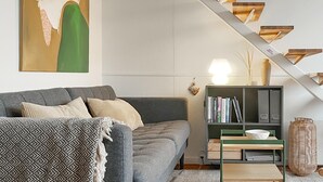 En moderne stue med en grå sofa, en reol og en trappe med trætrin.