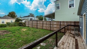 A backyard with a wooden deck, a covered patio, and a fenced area.