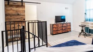 A bedroom with a bed, a TV, a dresser, a ceiling fan, and a sliding barn door.