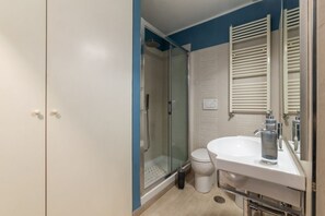 A bathroom with a glass-enclosed shower, a white sink, and a toilet.