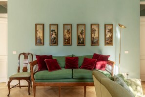 A living room with a green sofa, red cushions, a wooden chair, and a floor lamp. - Santa Maria alle Fornaci - FromHometoRome (Rome)