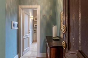 A hallway with a wooden door, a white door leading to a room, and a small table with a green tray.