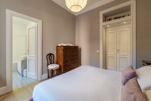 A bedroom with a large bed, a dresser, a chair, and a bookshelf.