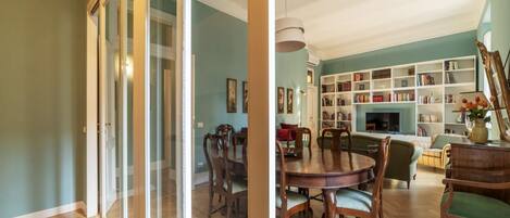 A dining area with a wooden table and chairs, a bookshelf, and a fireplace.
