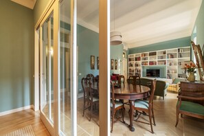 A dining area with a wooden table and chairs, a bookshelf, and a fireplace.