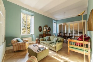 A spacious living room with a large window, a sofa, a striped armchair, and a wooden bench. - Santa Maria alle Fornaci - FromHometoRome (Rome)
