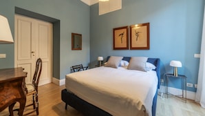 Een slaapkamer met een groot bed, een houten bureau, een stoel en twee wandlampen.