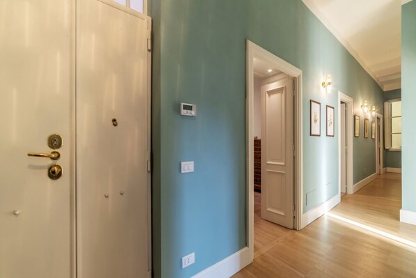 A hallway with teal walls, wooden flooring, and white doors.