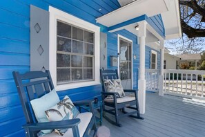 A porch with two rocking chairs, a white railing, and a blue house. - 7minWalk2Beach/Games/Playground/FamilyTime/BBQ (Gulfport)