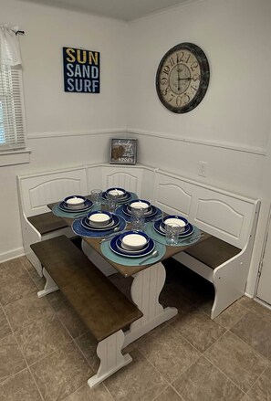 A dining table set for four with blue and white plates, glasses, and a clock on the wall. - 7minWalk2Beach/Games/Playground/FamilyTime/BBQ (Gulfport)
