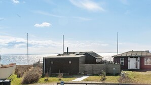 A coastal property with a brick building and a small red house, both with visible windows and doors, and a clear view of the sea in the background. - 2 bedroom gorgeous home in Juelsminde (Juelsminde)