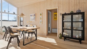 A dining area with a wooden table and chairs, a cabinet with glass doors, and a view through a window. - 2 bedroom gorgeous home in Juelsminde (Juelsminde)