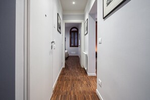 Un couloir étroit doté d’un plancher en bois, de murs blancs et de tableaux encadrés.