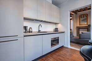 Une cuisine moderne avec des meubles blancs, un four en acier inoxydable et une machine à café.