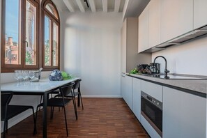 A compact kitchen with a dining area, a built-in oven, and a window with a view of buildings.