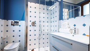 A modern bathroom with a glass-enclosed shower, a white toilet, and a vanity with a mirror. - Ca' Vida Trifora (Venezia)