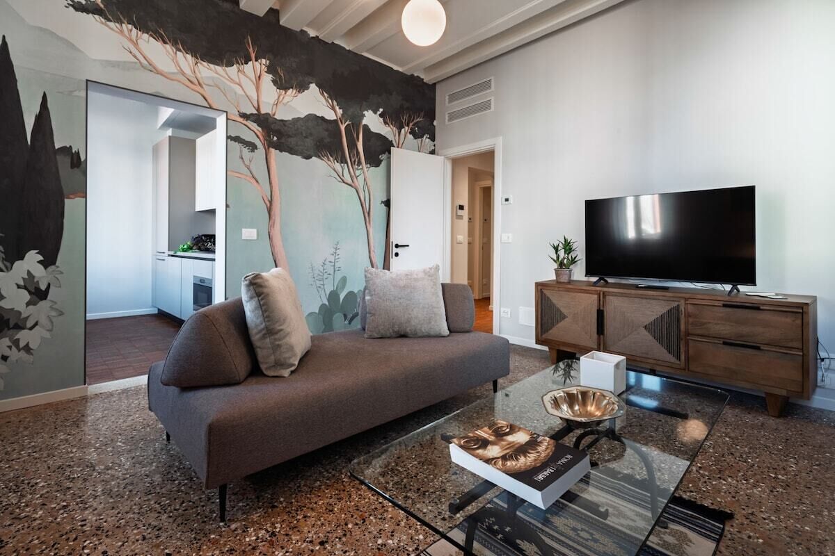 Un salon moderne avec un canapé, une table basse en verre, un téléviseur à écran plat et un meuble en bois.