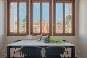 A dining area with a table, chairs, and a window with a view of buildings.