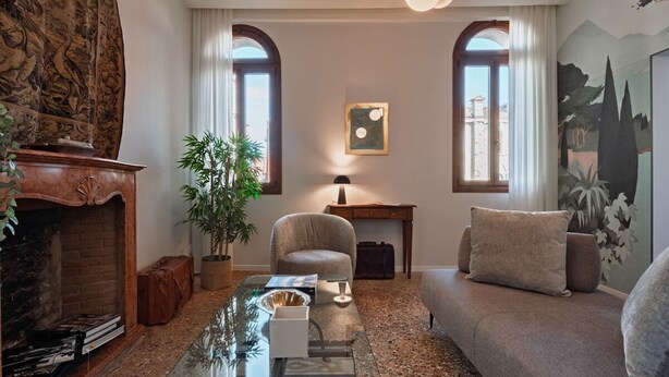 A living room with a fireplace, a sofa, a coffee table, and a large window. - Ca' Vida Trifora (Venezia)