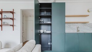 A modern kitchen with teal cabinets, a marble countertop, and a built-in wine rack. - Blueground | Bastille, near shops & park (Paris)