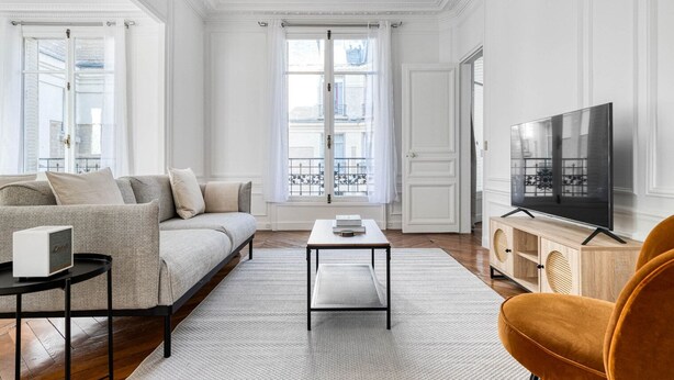 Una sala de estar con un sofá, una mesa de centro, un televisor y un sillón.