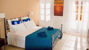 A neatly made bed with white and blue pillows, a blue bedspread, and a pair of shoes on the footboard. - Case Vacanze Il Sorriso (Catania)